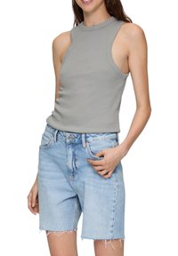 Grijze mouwloze top met een hoge halslijn, gedragen met lichtblauwe denimshorts met rafelige zomen en zijzakken.