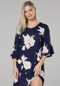 Navy floral dress with white and peach flowers, V-neckline, and flared sleeves. Features side slit for ease of movement. Made from lightweight fabric.