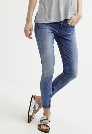 Skinny jeans in een lichte blauwe wassing, met een gladde textuur en een klassiek vijf-pocket ontwerp. Gecombineerd met metallic zilveren sandalen.