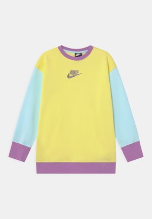 Bluza Nike z żółtym korpusem, jasnoniebieskimi rękawami oraz fioletowymi mankietami. Na środku znajduje się szare logo, prezentujące wzór w stylu color-block.