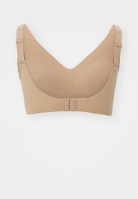 Nude seamless bra with a V-neck design, padded cups, adjustable straps, and a hook-and-eye closure at the back. Soft texture.