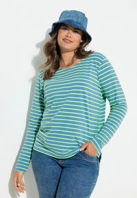 Pitkähihainen paita sinisin ja limenvihrein raidoin, valmistettu pehmeästä kankaasta. Yhdistetty rentoon farkkulierihattuun, jossa on väljät mitat ja pyöreä pääntie.