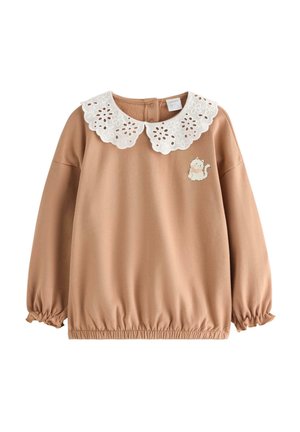 Tan long-sleeve toddler shirt with elastic cuffs and hem, white eyelet lace collar, and small embroidered white cat on the chest.