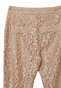 Pantalons en dentelle beige clair, présentant des motifs floraux et une surface texturée. Comprend deux poches arrière et une ceinture lisse.