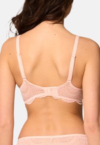Ljusrosa spetsbehå med scallopade kanter, justerbara remmar och bakre hysk. Har intrikata spetsdetaljer.