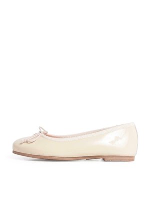 Ballerine couleur crème avec un petit nœud à l’avant et une semelle plate en bois, vue de côté sur fond blanc.