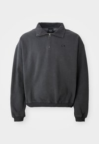Mørkegrå langermet genser med halv-zip krage, ribbestrikkede mansjetter og hem, samt en liten svart logo-lapp på venstre bryst.