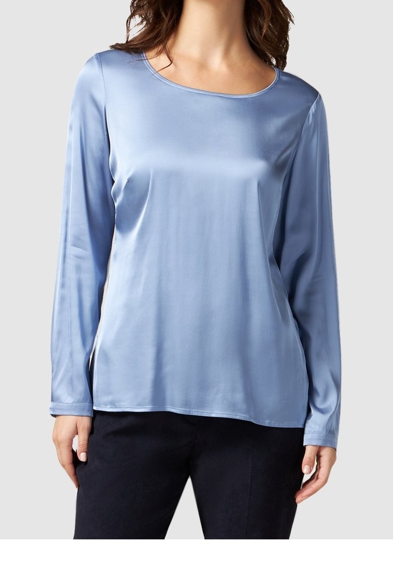 Light blue long-sleeve blouse made of satin with a round neckline and a smooth texture. Features a relaxed fit and side slits.
