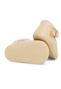 Stivaletti beige in pelle con punta arrotondata, texture liscia, una cinghia laterale con fibbia e suola in gomma solida.