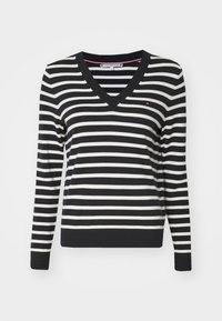Striped V-neck sweater in black and white, featuring long sleeves and a ribbed hem, with a small logo detail on the chest.