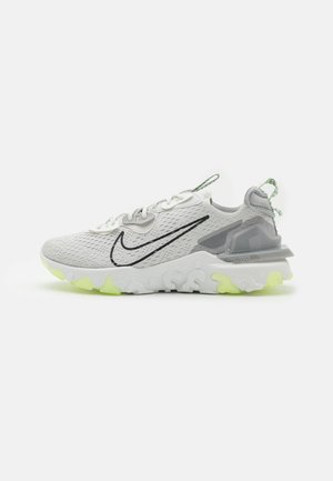 Baskets de sport grises avec une tige en mesh respirant, un swoosh noir et une semelle blanche texturée avec des accents vert néon.