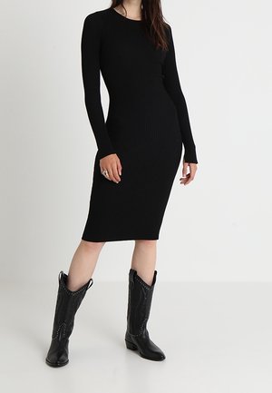 Abito midi nero a costine con maniche lunghe, forma aderente e scollatura tonda. Abbinato a stivali cowboy neri con cuciture decorative.