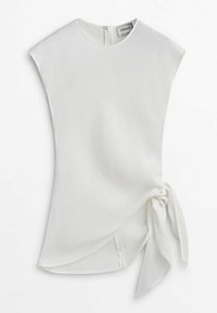 Haut blanc sans manches avec une texture douce, présentant un détail de nœud sur le côté et un col rond, fermé par une fermeture éclair dissimulée au dos.