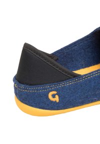 Blue felt slipper featuring a black fabric heel, yellow rubber outsole, and embroidered orange “G” logo. Smooth texture with a casual design.
