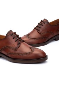 Chaussures habillées en cuir marron avec un bout pointu, motif brogue détaillé et lacets assortis. Texture lisse et poli avec un talon bas.
