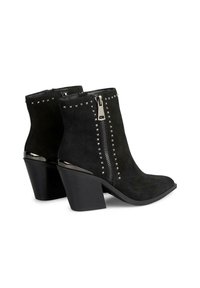 Stivali ankle in suede nera con punta affusolata, tacco medio a blocco, zip laterale e borchie argentate lungo il colletto.