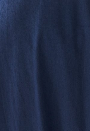 Tessuto blu navy con una texture liscia, che mostra sottili variazioni di tonalità e luce, indicando un materiale leggero.