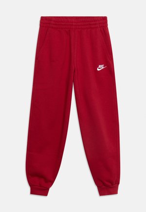 Pantalon de survêtement rouge Nike avec taille et poignets élastiques, poches latérales et logo Nike blanc sur la cuisse gauche.