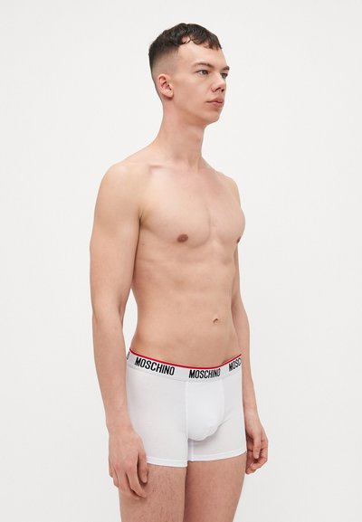 White cotton boxer shorts with a black and red Moschino logo waistband, featuring a fitted design and smooth texture.