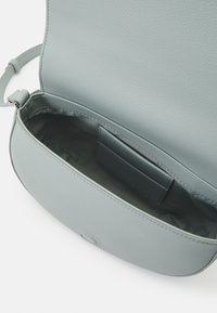 Borsa a tracolla in pelle blu chiaro con un'esterno strutturato, chiusura a pattina e una tasca interna con slot per carte.