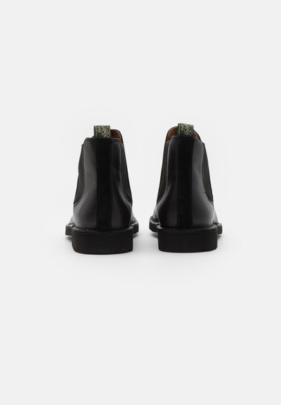 Botas Chelsea de cuero negro con acabado suave, paneles laterales elásticos y tiradores de marca verdes en la parte posterior. Suelas de goma resistentes.