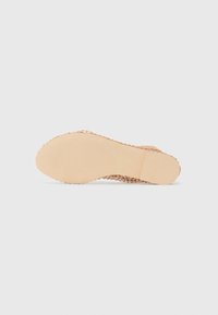 Semelle de sandale tan avec une texture et un design tissé. Dotée d'un talon plat et d'une surface lisse, présentant des détails minimaux.