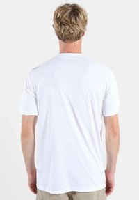 T-shirt blanc à manches courtes avec col rond, présentant une texture lisse et un petit logo sur l'épaule.