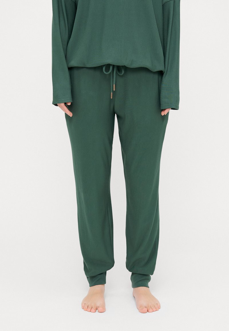 Green lounge set made of soft fabric. Top has a relaxed fit and long sleeves; pants feature an elastic waistband and tapered cuffs.