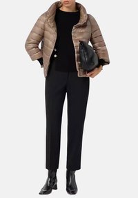 Giubbotto imbottito di colore marrone chiaro, con colletto alto e design trapuntato. Top aderente nero, pantaloni neri su misura e stivaletti neri con punta appuntita.