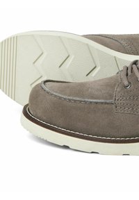 Scarpe in suede grigio con suola in gomma bianca caratterizzate da un motivo a zigzag, cuciture dettagliate e una punta arrotondata.