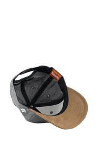 Gray and black cap with a tan suede bill, featuring a leather tag labeled "Pumuckl," and six ventilation holes on the crown.