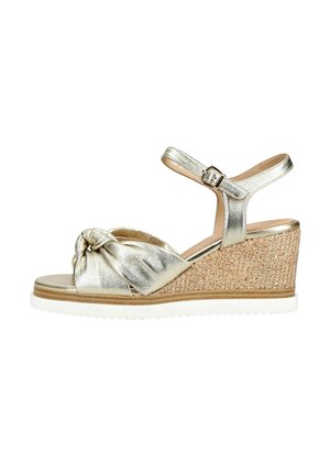 Sandalo zeppa metallizzato dorato con cinturino frontale annodato, fibbia alla caviglia, tacco intrecciato e suola bianca rigata.