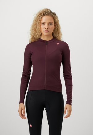 Burgunderfarbener, langärmliger Radjacke mit Reißverschluss, taillierte Passform, glatte Textur, mit kleinem Logo auf der linken Brust, kombiniert mit schwarzen Fahrradhosen.