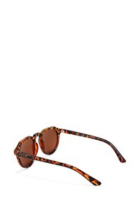 Kulaté sluneční brýle s želvovinovým rámem a hnědými skly. Jsou vybaveny širokými vzorovanými ramínky s logem značky na jedné straně.