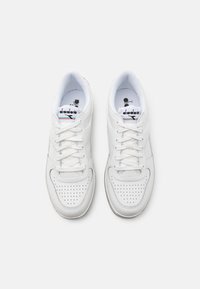 White athletic sneakers with a leather upper, perforated detailing, flat laces, and a cushioned insole for comfort. Diadora branding on tongue.