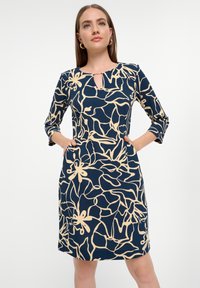 Marineblaues Kleid mit beigem Blumenmuster, Dreiviertelärmel, Schlitzkragen-Detail und Seitentaschen, aus glattem Stoff gefertigt.