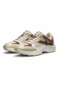 Beige and brown athletic shoes with a mesh upper, padded collar, and pink accent on the heel. Thick white midsole, textured rubber outsole.