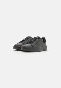 Sneakers neri con tomaia in pelle liscia, dettagli in tessuto, chiusura con lacci e suola in gomma texturizzata, caratterizzati da un design a taglio basso.