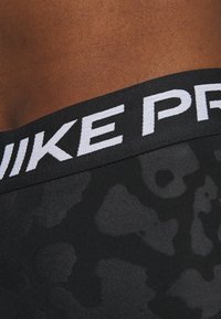 Czarne sportowe szorty z teksturowanym, wzorzystym materiałem. Posiadają szeroki elastyczny pas z białym napisem "NIKE PRO".