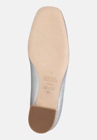 Semelle de chaussure en cuir argenté avec une texture lisse, dotée d'un talon brun surélevé et de détails de marque en relief. Taille 37.