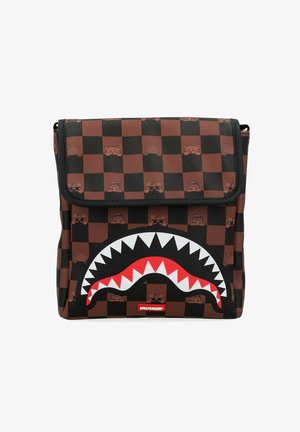 Bolsa de cuadros marrón y negro con dibujos de oso de caricatura e íconos de objetos, con un gran diseño de boca de tiburón blanca y roja en la parte frontal.