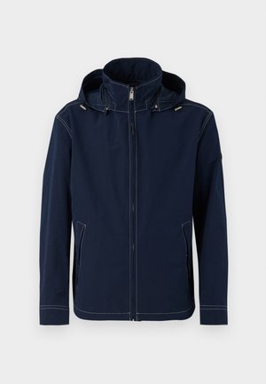 Navy sininen takki, jossa on korkea kaulus, täysi vetoketju edessä, sivutaskut ja erottuva valkoinen tikkaus. Varustettu irrotettavalla hupulla.