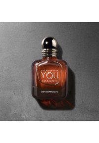 Bruine glazen parfumfles met een afgeronde, zwarte metalen dop. Etiket leest "STRONGER WITH YOU ABSOLUTELY" en "EMPORIO ARMANI" is op de bodem geperst.