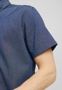 Košile s krátkými rukávy z tmavě modré džínové látky, s límečkem a ohrnutými manžetami, s hladkou texturou a jemným leskem.