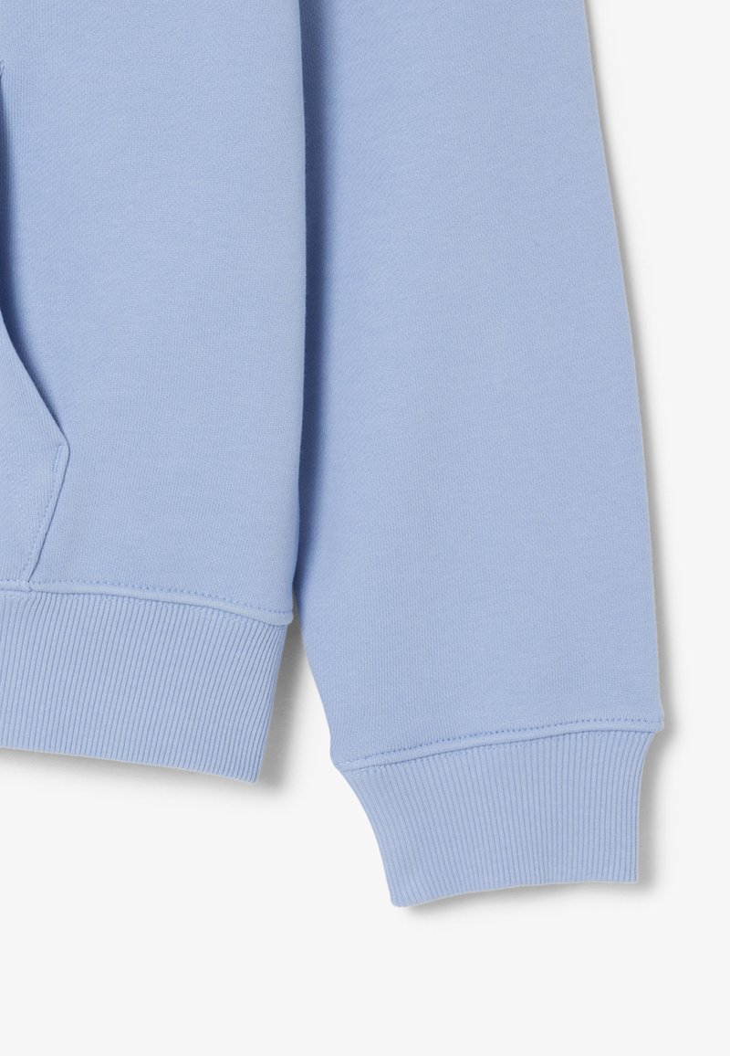 Manica di felpa azzurro chiaro con polsino a coste e tasca frontale parziale visibile su sfondo bianco.