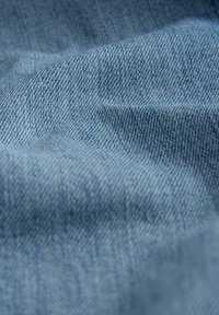 Helehelesin sinine denim kangas, millel on tviillkoes, näidates õrnu värvi ja tekstuuri erinevusi, sobilik erinevate rõivaste rakendamiseks.