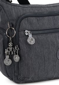 Dark gray fabric shoulder bag with a textured pattern, featuring a zippered pocket and metal hardware accents, including a charm and logo tag.