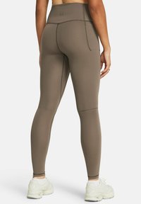 Höga bruna leggings gjorda av stretchigt material med platta sömmar, med en fickdetalj och en avsmalnande passform.