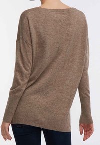 Bruine, oversized gebreide trui met een brede halslijn, doorgezakte schouders en geribde manchetten. Zachte textuur en een casual pasvorm.