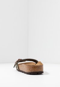 Brun korksål sandal med en grøn stofrem. Har en tekstureret fodseng og justerbar spænde. Set fra siden.